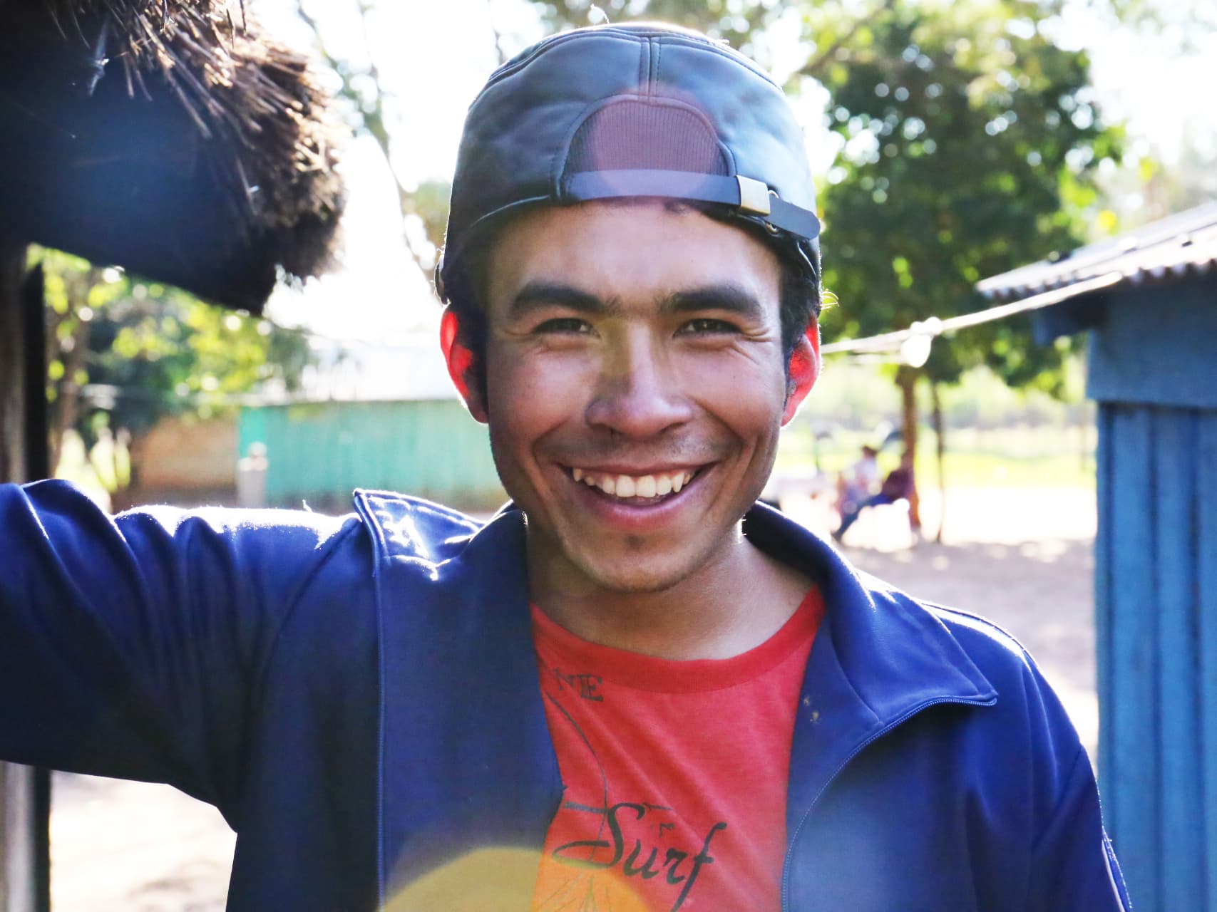 A young man with a cap smiling.