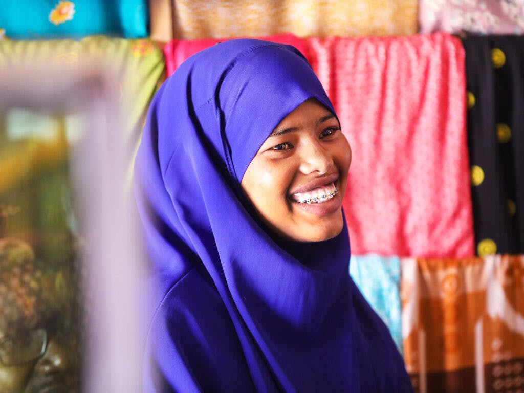 A smiling Somali woman wearing a purple hijab.