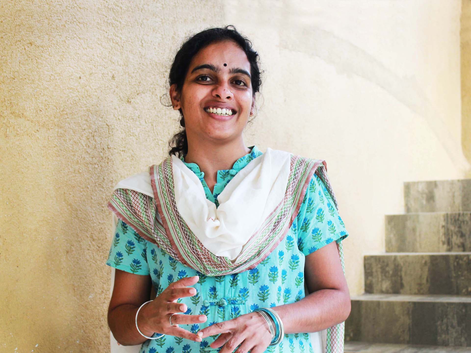 A smiling woman standing in front of some stairs.