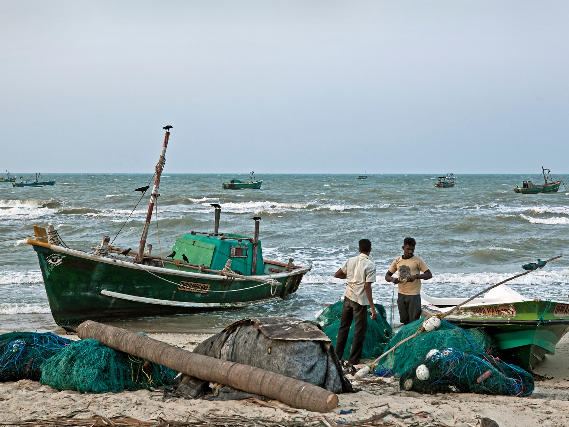 Two fishermen and a boat at the beach.