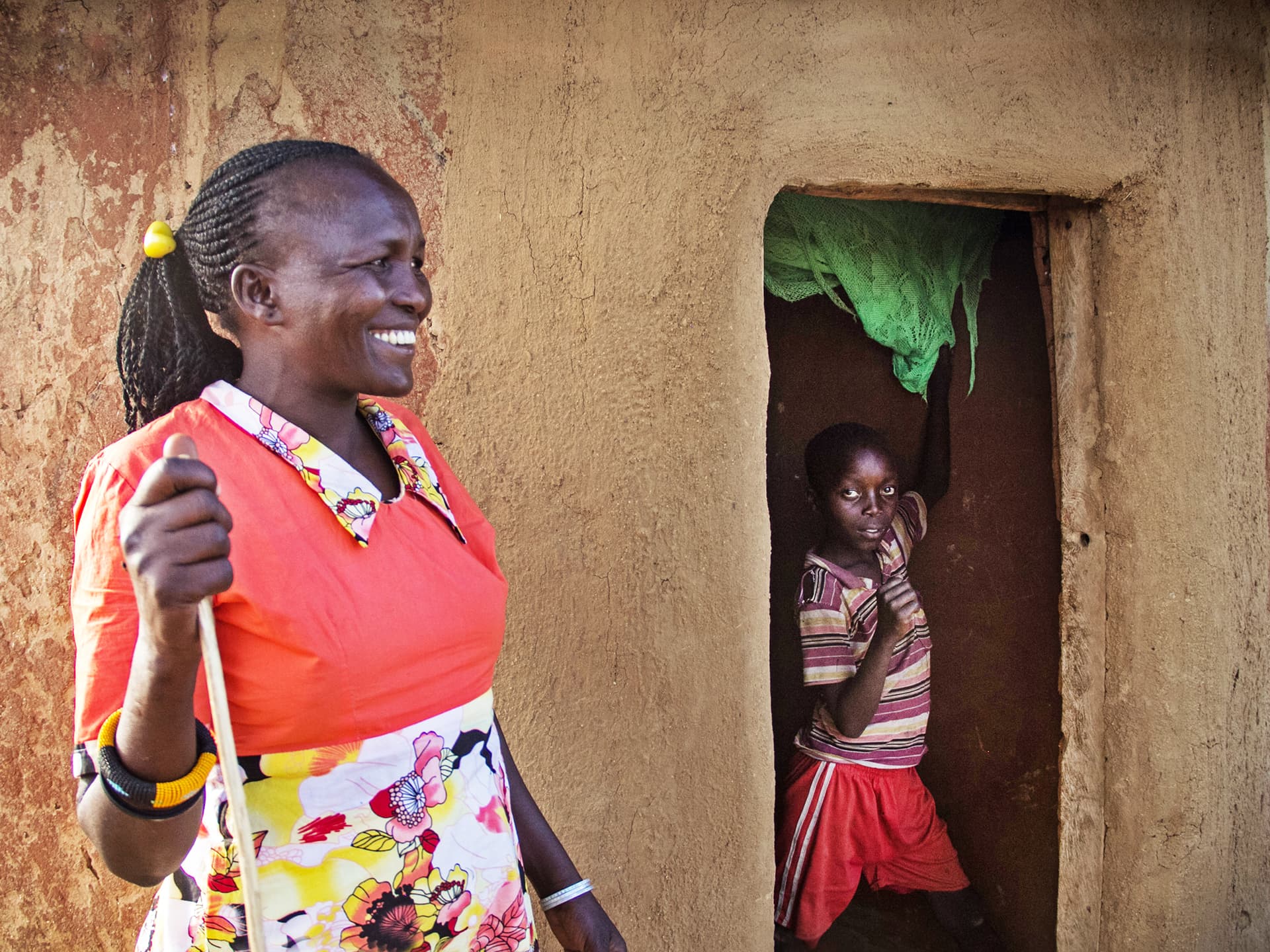 Woman standing outside a house. A child is standing in the door.