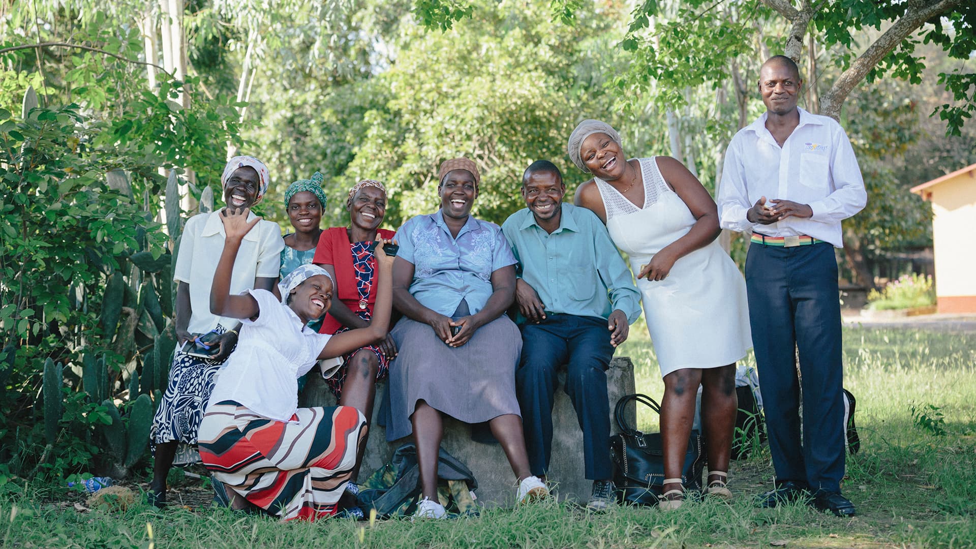 A group of Zimbabwean men and women outside in a green field with trees in the background.