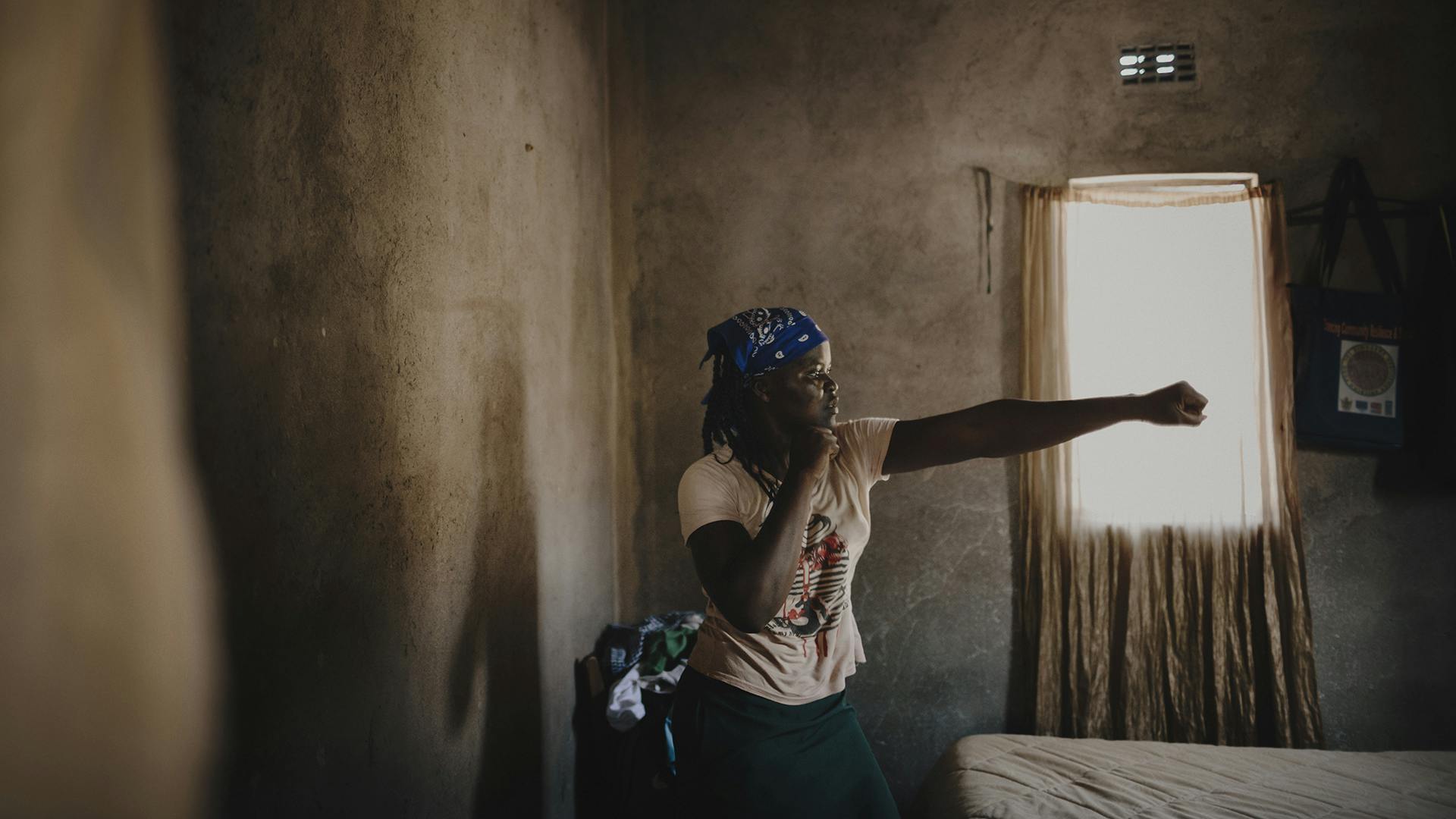 A Zimbabwean woman in a room doing a boxing pose.