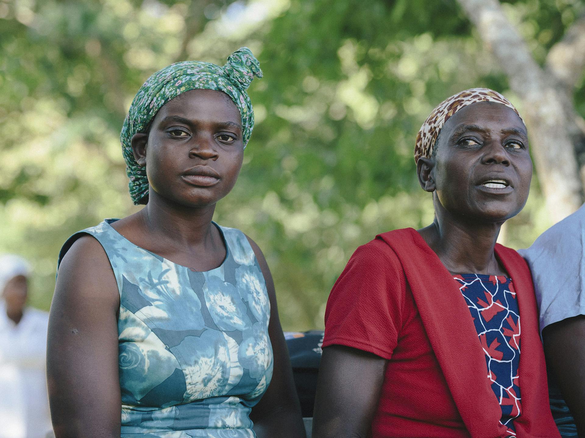 Two Zimbabwean women sitting next to each other. Behind them there are trees.