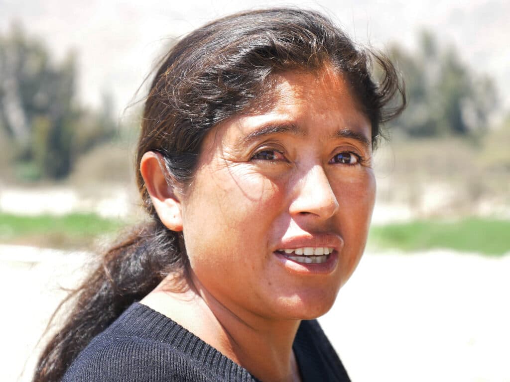 A closeup of a woman standing outside in a field.