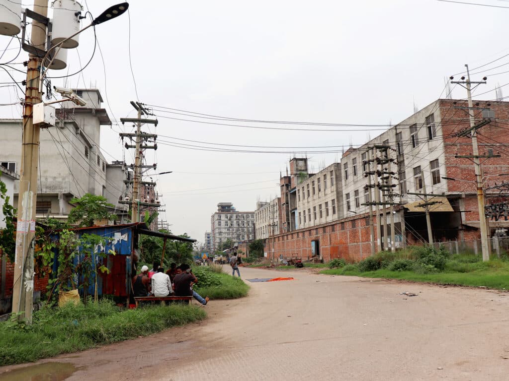 A street view with some people sitting by the side of the street.