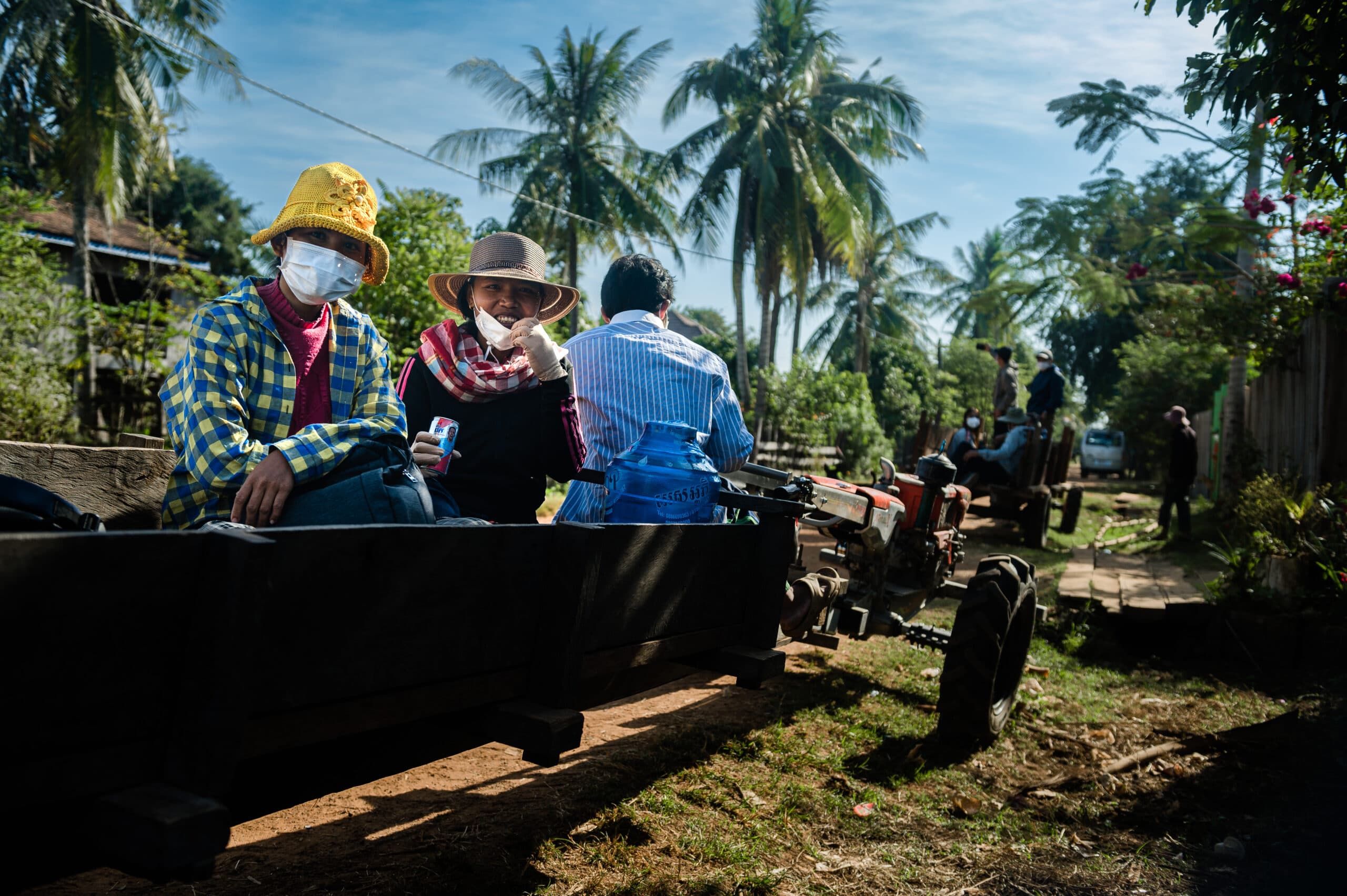 A group of people sitting on a carriage, in the background there are trees.