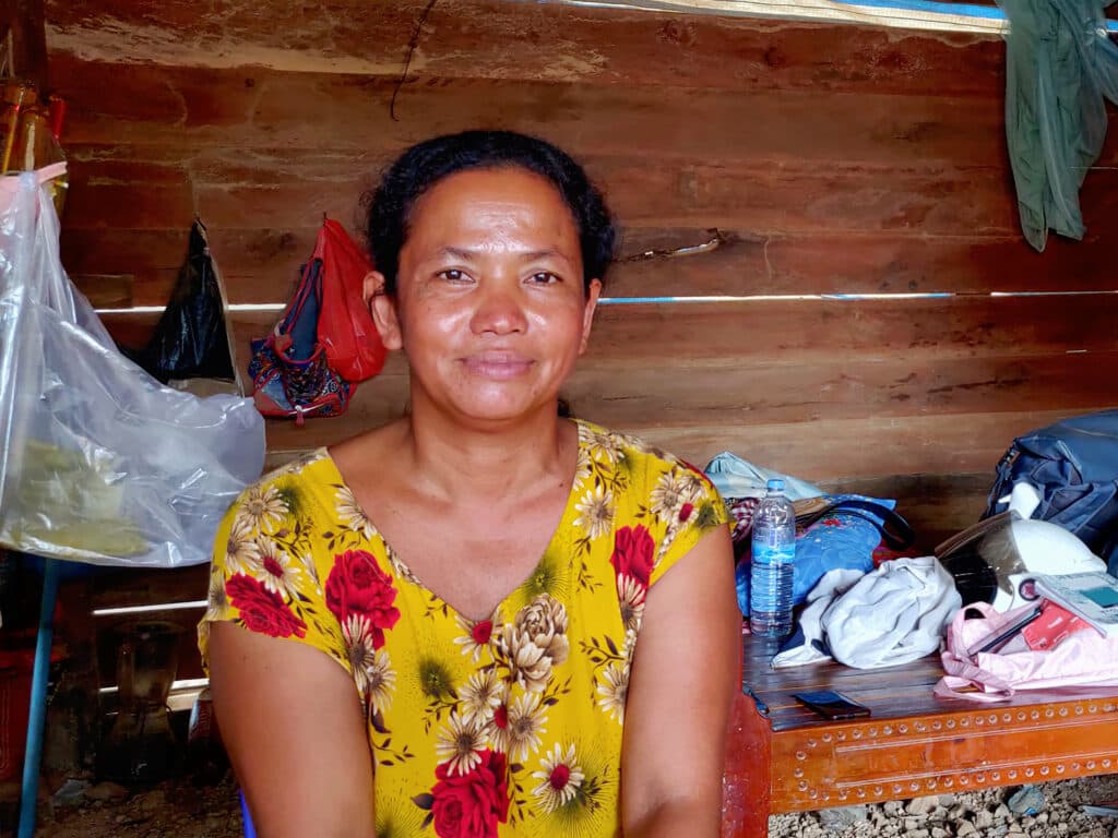 A woman sitting in a house with a wooden panel in the background.