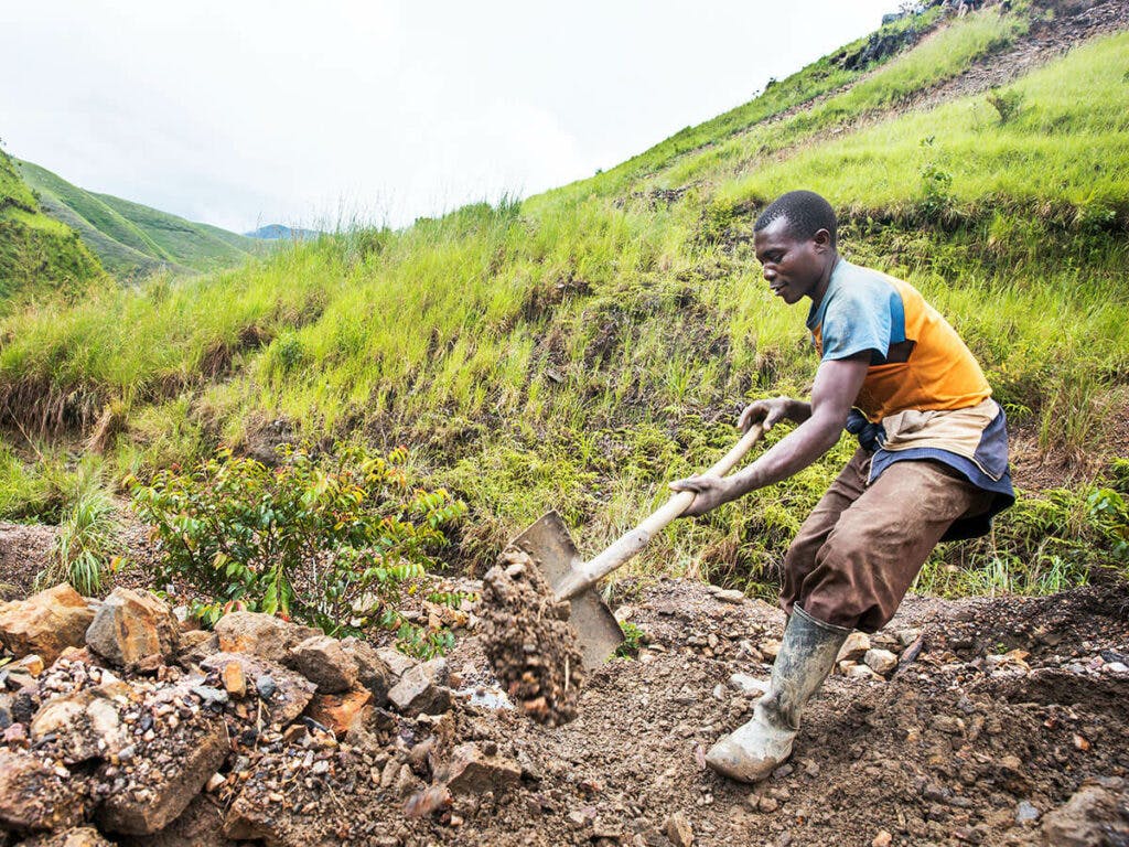 A Congolese man using a shovel in a field.
