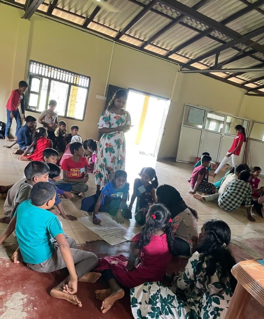Photo: VILUTHU A group of young students sitting on a floor.