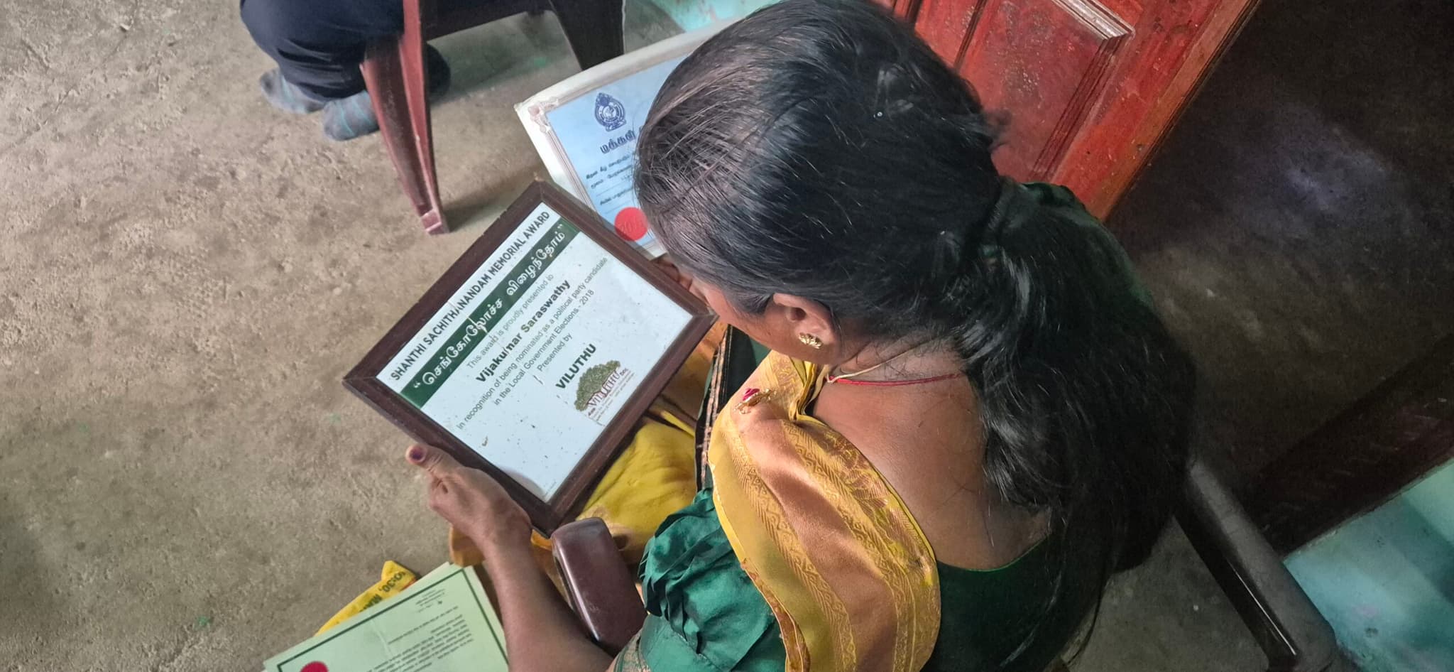South Asian woman looking at the award certificate