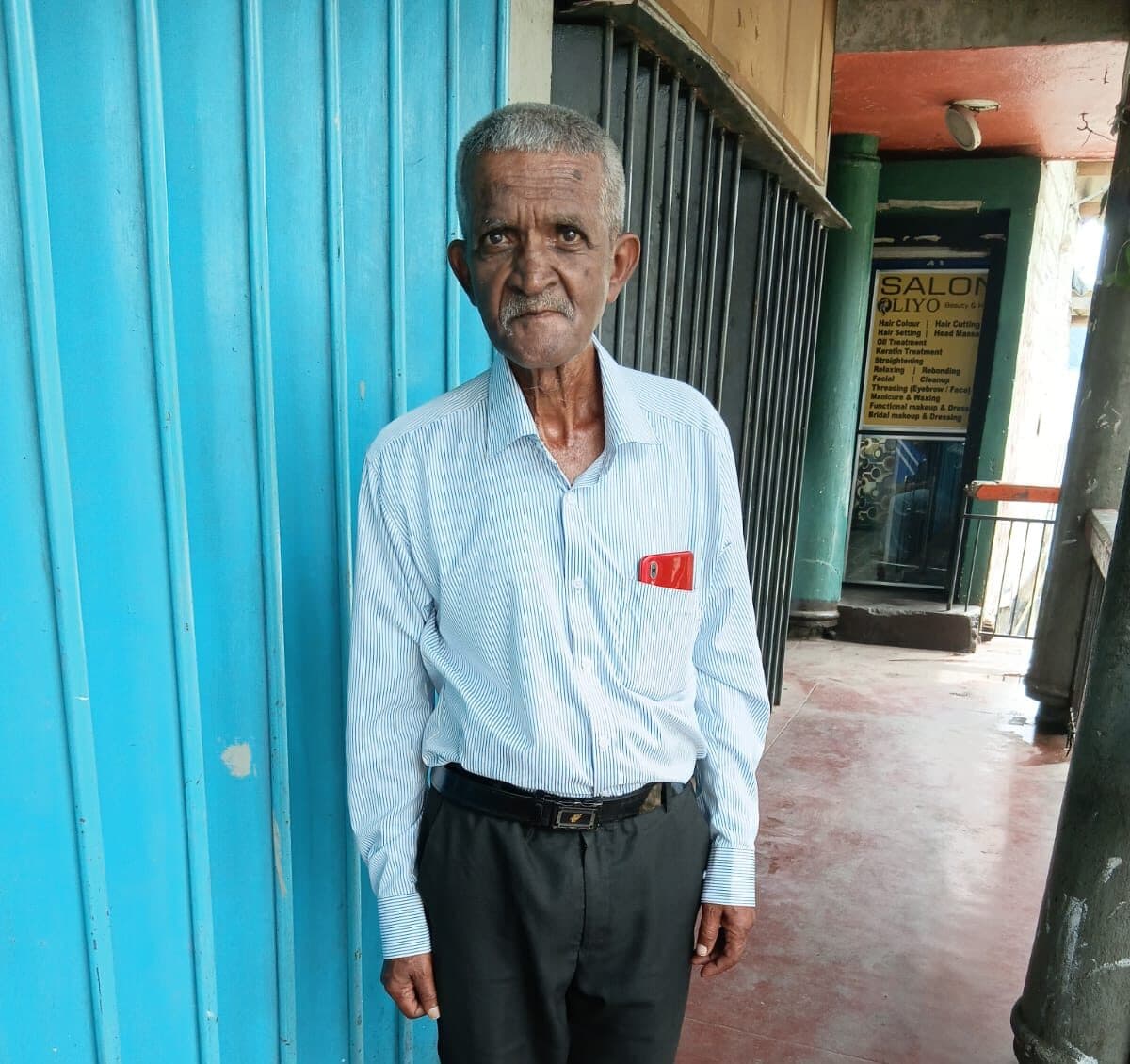 A senior man standing in front of the blue gate