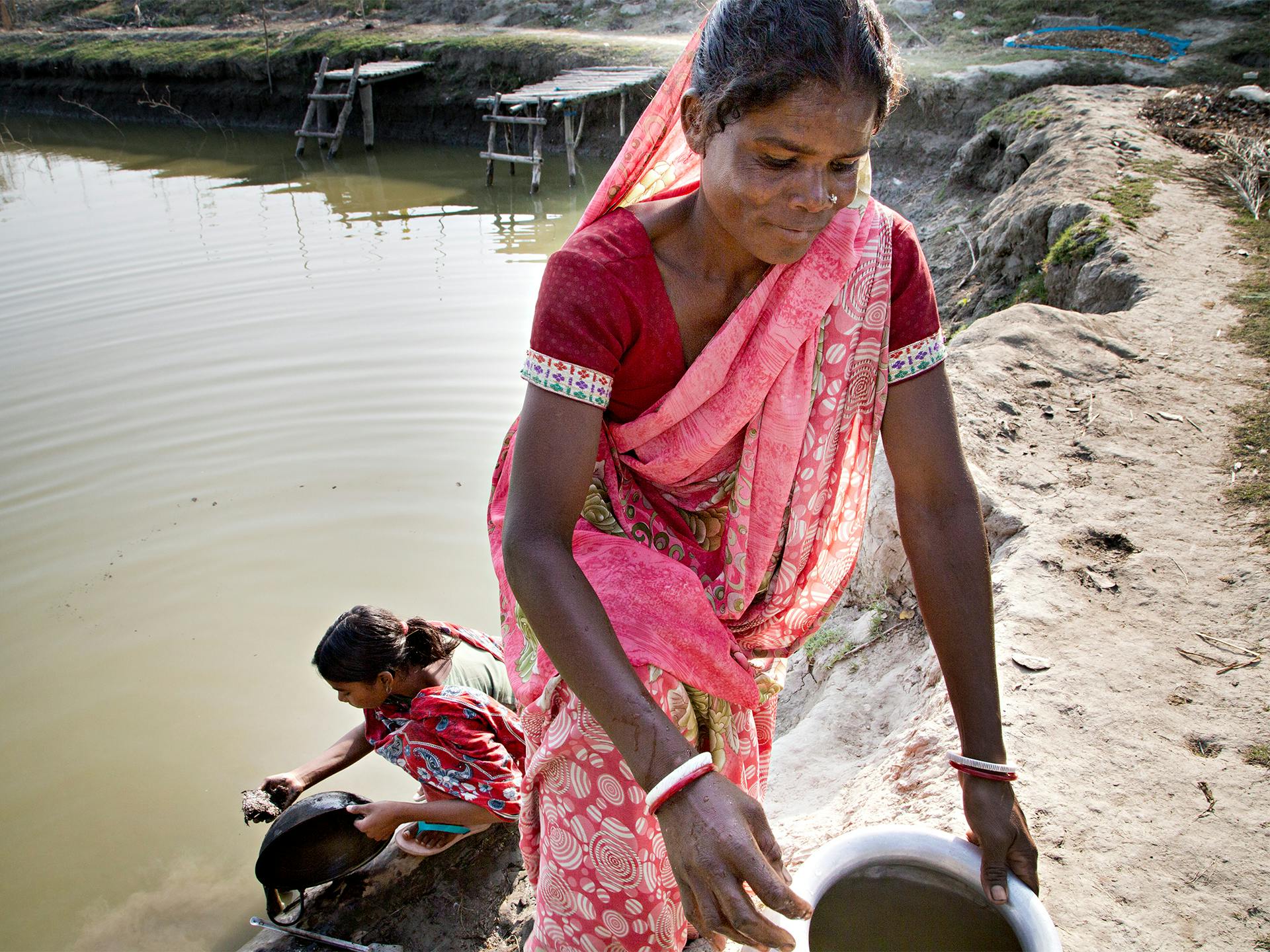 Kvinna i Bangladesh hämtar vatten i damm