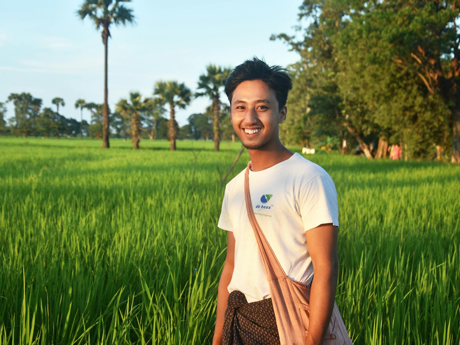 En ung man står i ett öppet grönt fält.