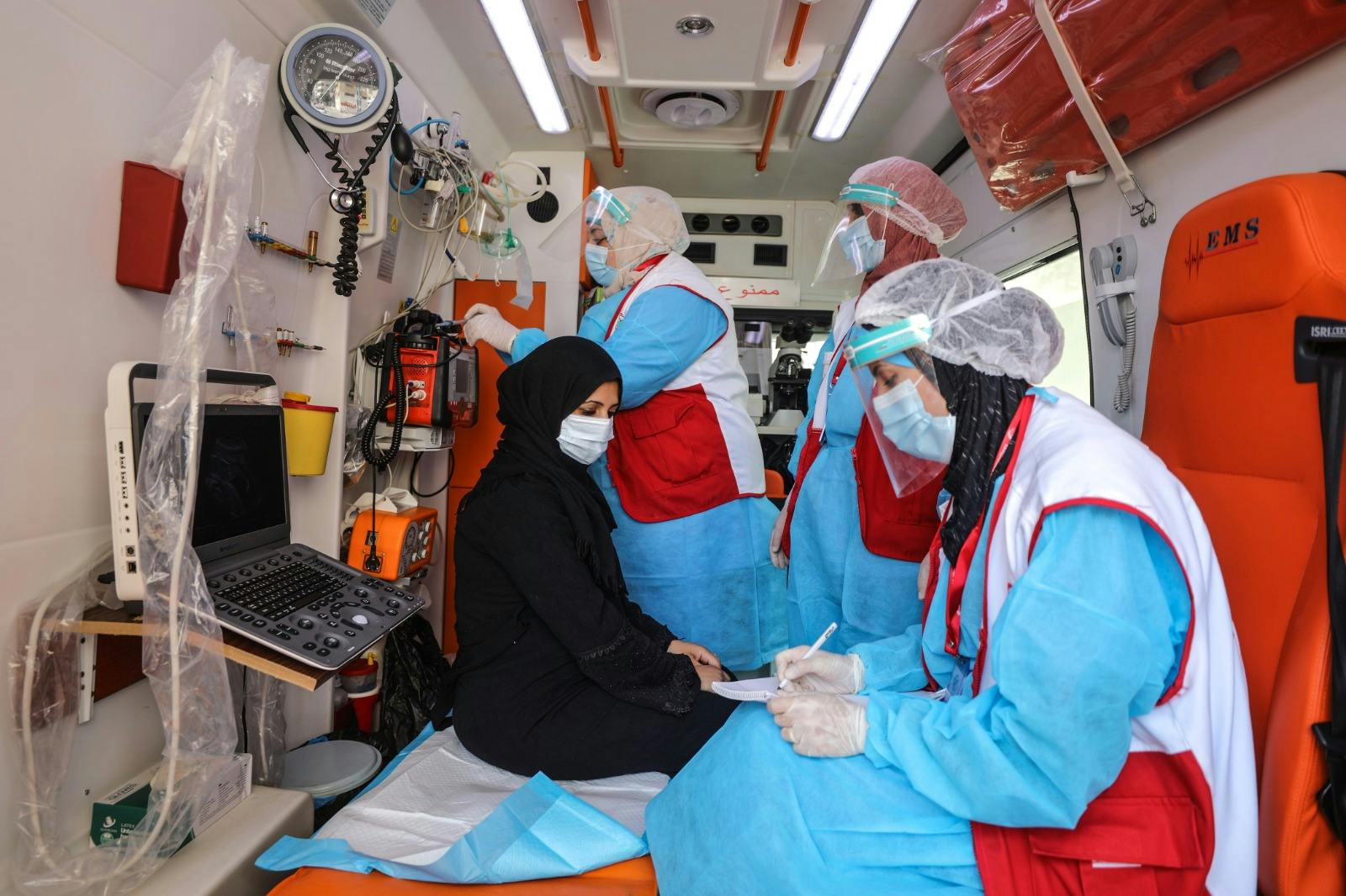 Medial personnel examine a woman in an ambulance car.