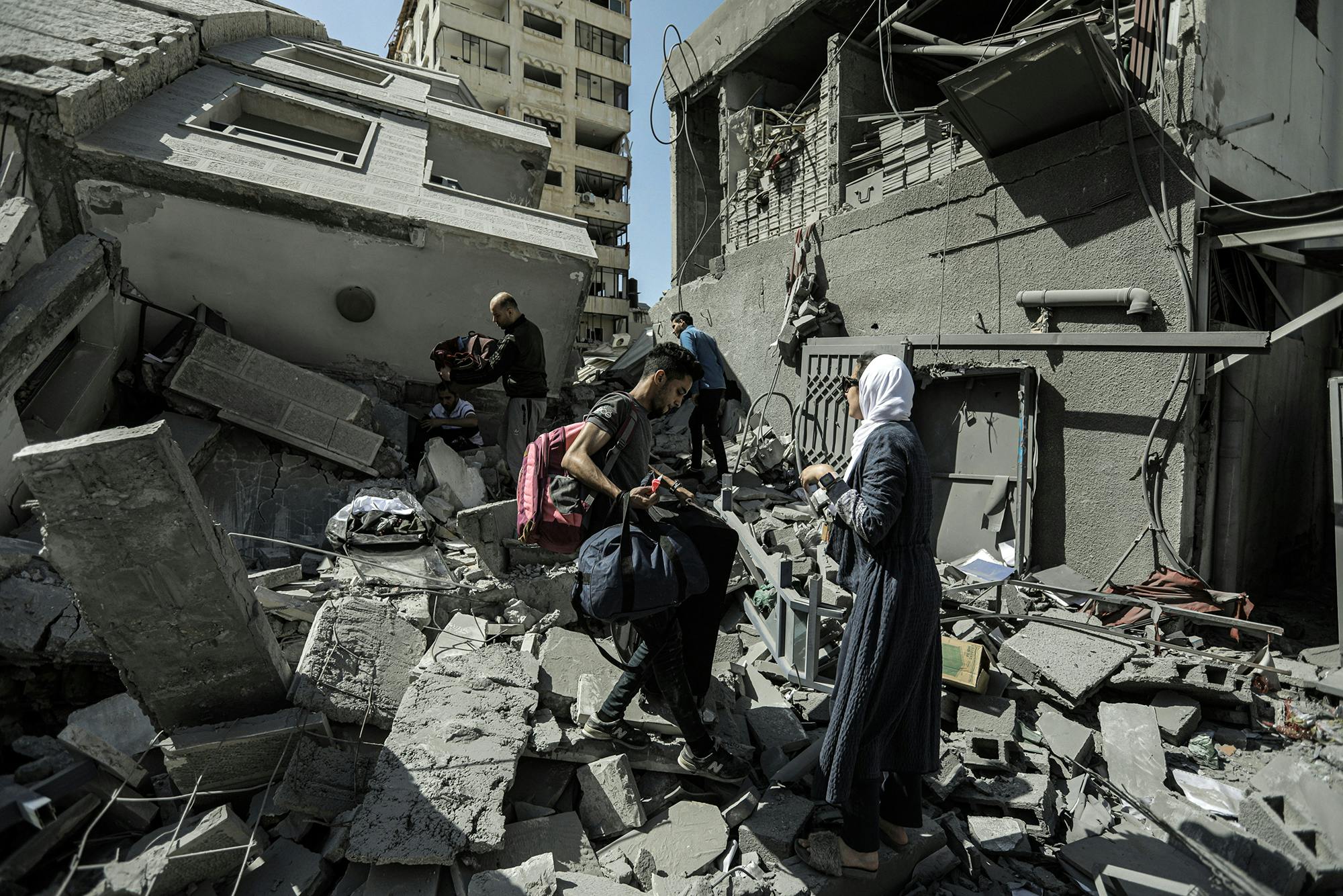 People climbing over the rubble of a destroyed building.