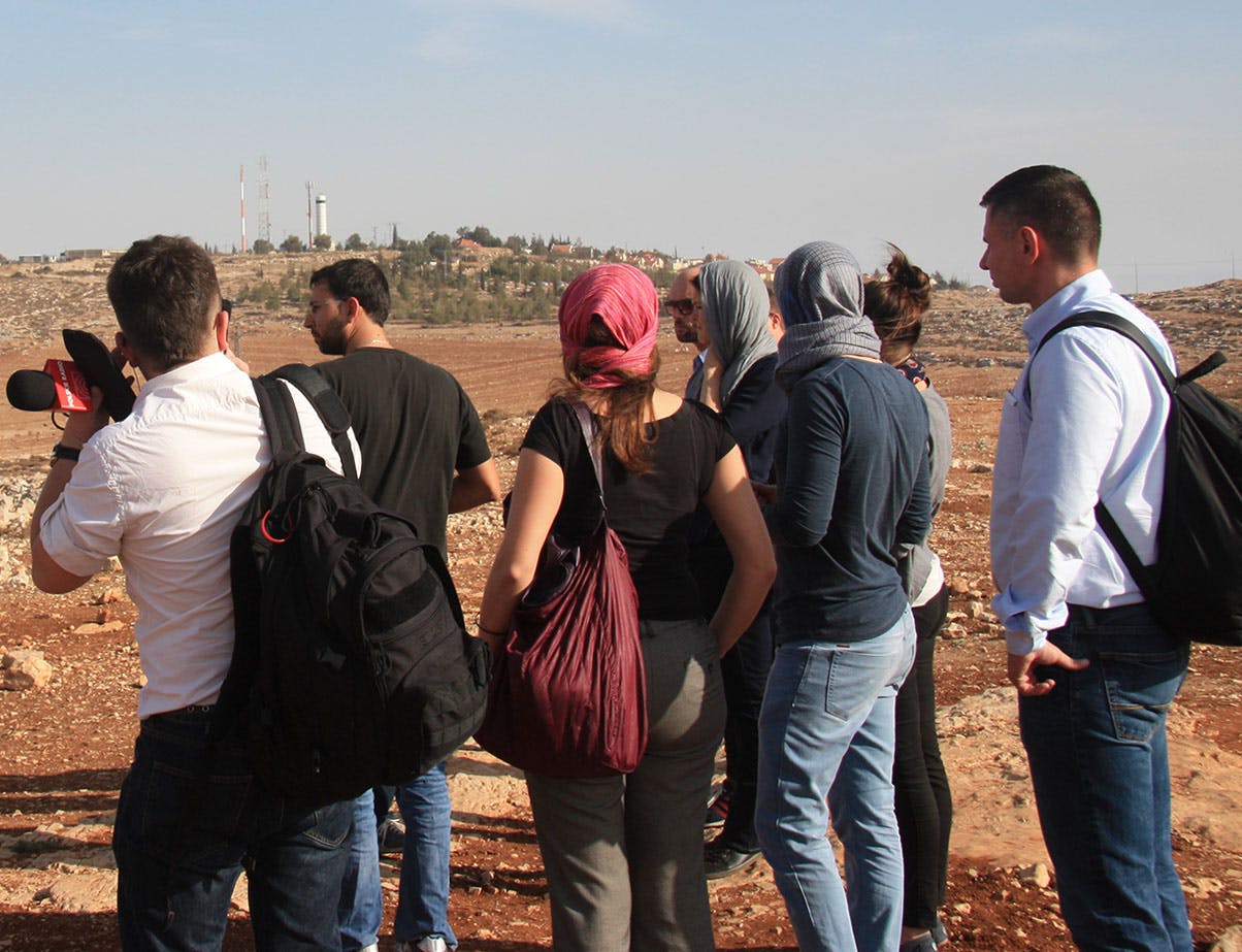 A group of journalists in front of a hill.