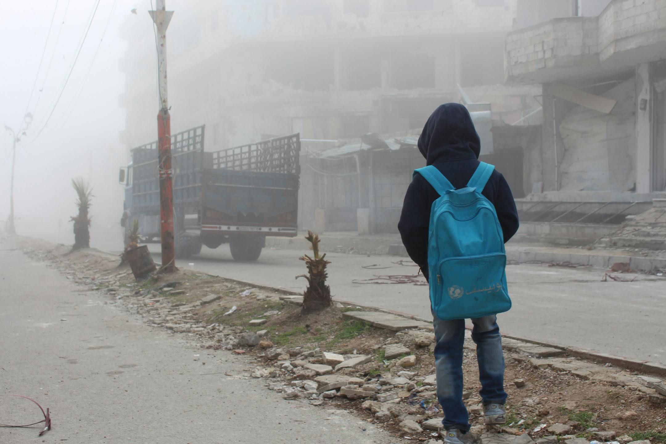 A child watching a truck that carries humanitarian aid.