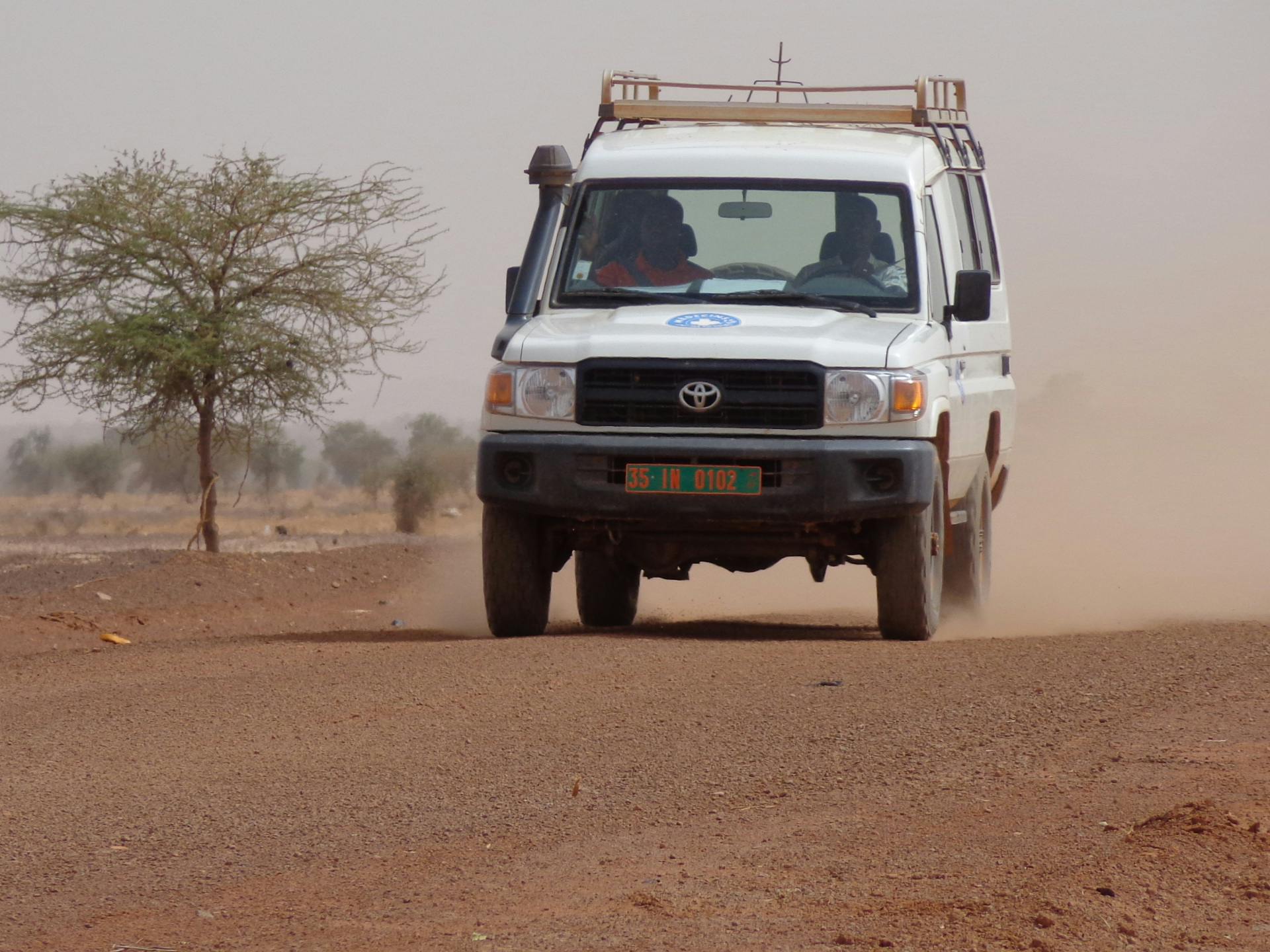A car of a humanitarian organisation providing is driving through the dessert.