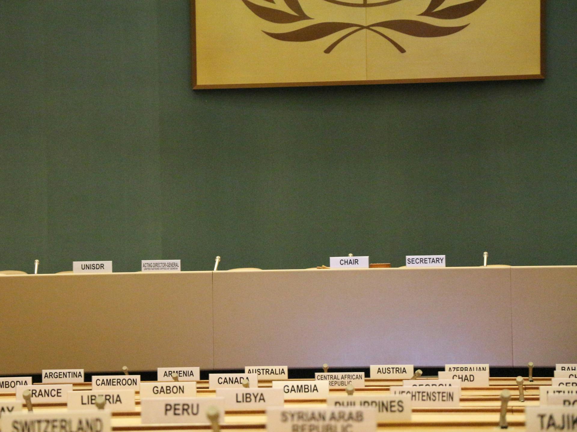 A meeting room of the United Nations with signs of country names.
