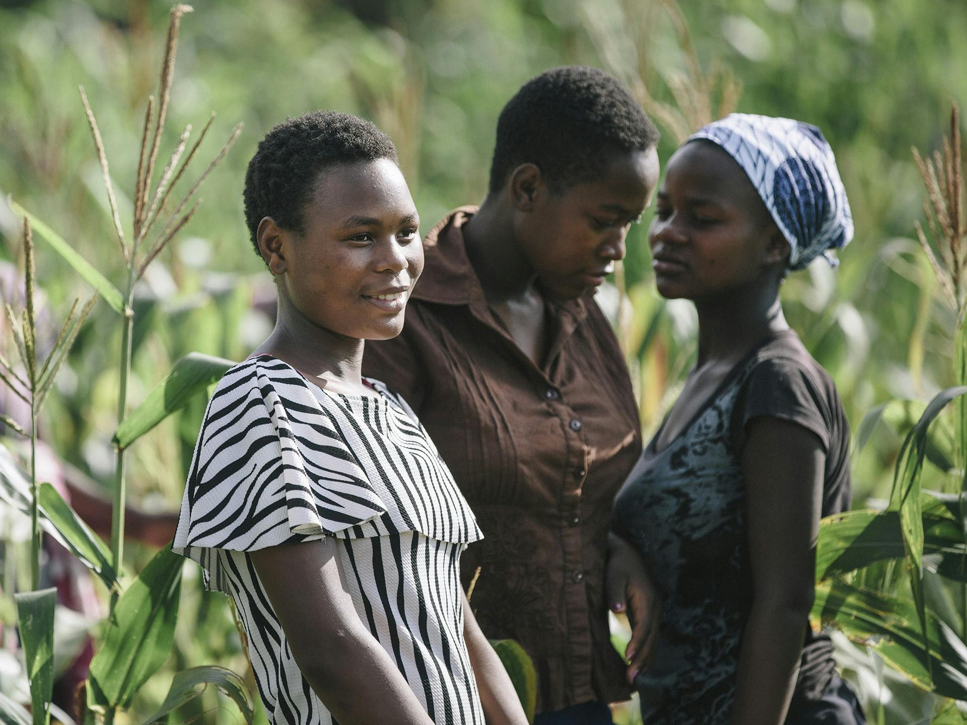 Three Zimbabwean women standing in a field of crops.