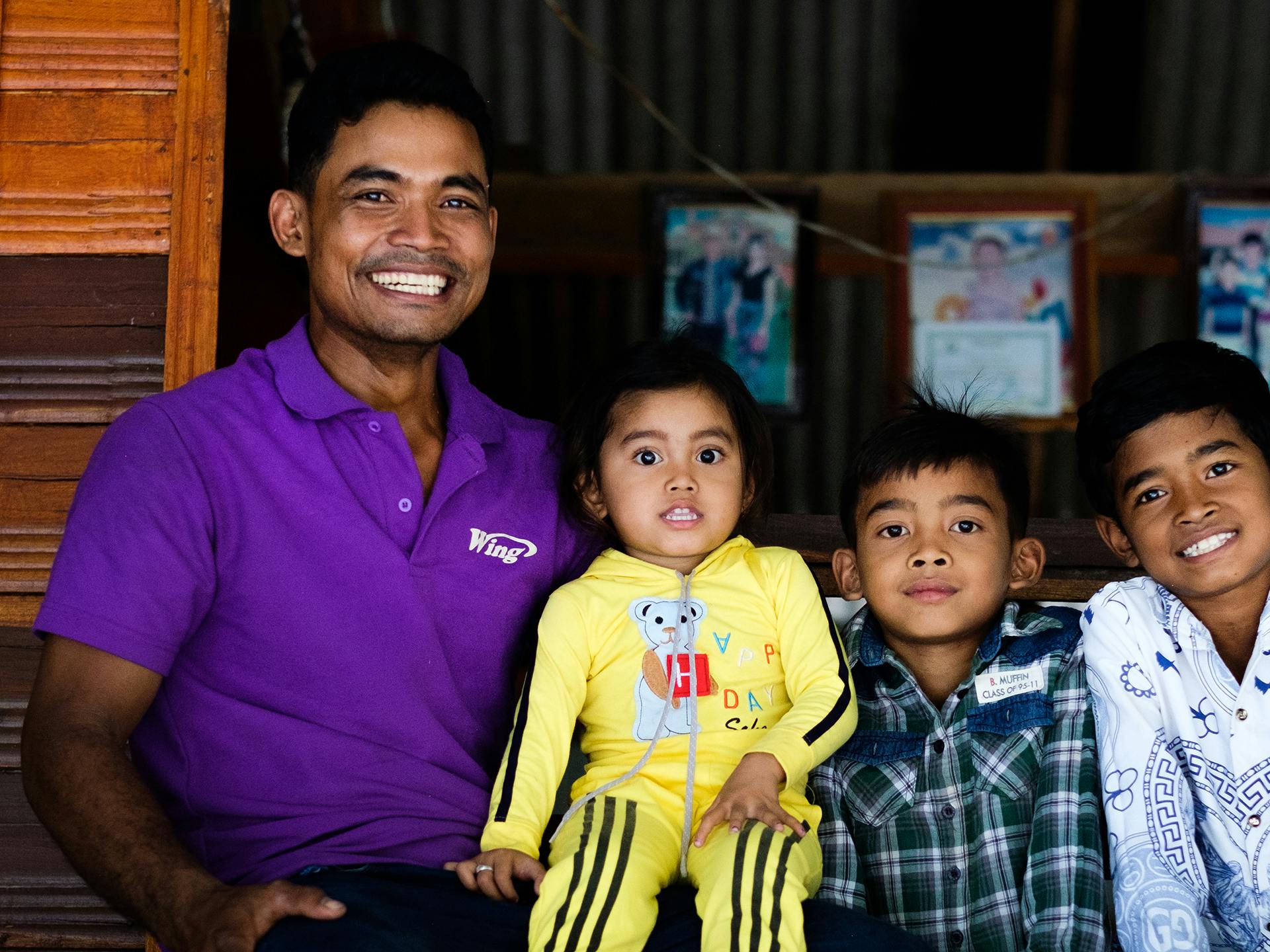 A smiling man together with three children looking in to the camera.